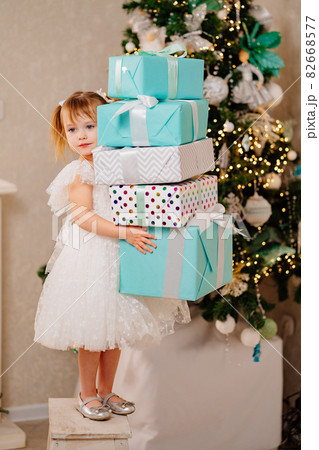 happy girl in a white dress with a gifts in his hands at the Christmas tree. happy girl in a white dress with a gifts in his hands at the Christmas tree. 82668577