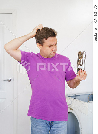 sad repairman of washing machine holds old tubular electric heater sad repairman of washing machine holds old tubular electric heater 82668578
