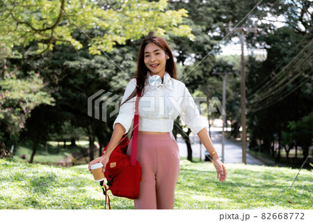 Portrait asian woman with headset hand holding a cup of coffee in ter garden 82668772