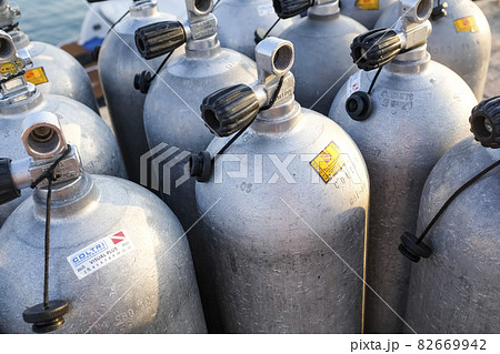 A lot of aluminum scuba diving oxygen tanks standing in front of the green beach bushes and rocks on the sand in Thailand with copy space A lot of aluminum scuba diving oxygen tanks standing in front of the green beach bushes and rocks on the sand in Thailand with copy space 82669942