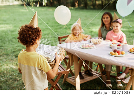 Boy Presenting Gifts at Birthday Party 82671083
