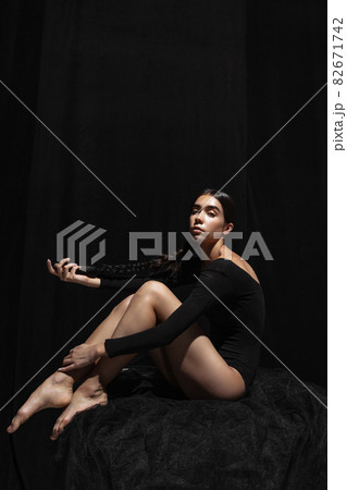 Portrait of young beautiful girl, modern ballet dancers posing isolated on dark background. Feelings, emotions concept Portrait of young beautiful girl, modern ballet dancers posing isolated on dark background. Feelings, emotions concept 82671742