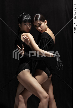 Modern ballet performance. Two beautiful girls, modern dancers in art performance isolated on dark background. Feelings, emotions concept Modern ballet performance. Two beautiful girls, modern dancers in art performance isolated on dark background. Feelings, emotions concept 82671754