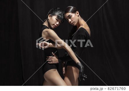 Modern ballet performance. Two beautiful girls, modern dancers in art performance isolated on dark background. Feelings, emotions concept Modern ballet performance. Two beautiful girls, modern dancers in art performance isolated on dark background. Feelings, emotions concept 82671760