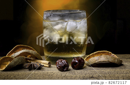 Herbal juice and fruit in a glass filled with ice and dried fruit and dried herbs placed on an old wooden table on blur bokeh background. Herbal juice and fruit in a glass filled with ice and dried fruit and dried herbs placed on an old wooden table on blur bokeh background. 82672117