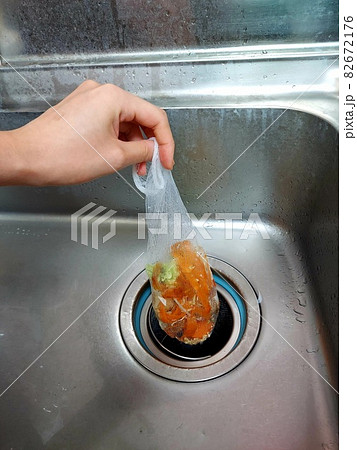 シンクの排水口に溜まった生ごみを持つ手 82672176