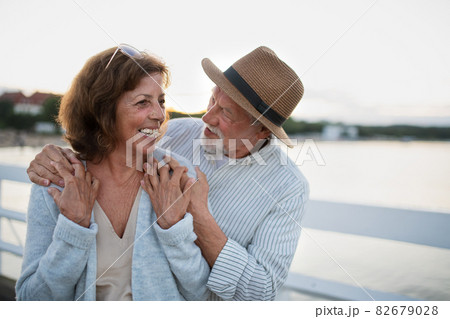 Happy senior couple in love hugging outdoors on pier by sea, looking at each other. 82679028