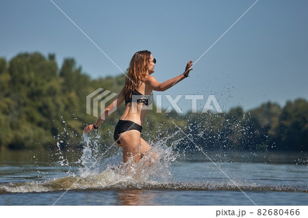 Girl at the beach running into the water Girl at the beach running into the water 82680466