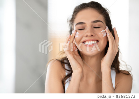 Lady Applying Facial Cream On Cheeks With Eyes Closed Indoor 82681572