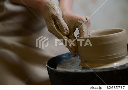 Close up of human hands making a bowl on a pottery wheel Close up of human hands making a bowl on a pottery wheel 82685737