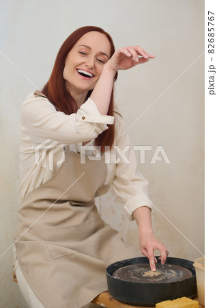 Female potter working on a pottery wheel in workshop 82685767