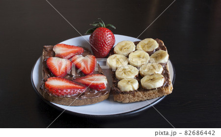 Two fruit sandwiches with chocolate paste, banana and strawberry 82686442