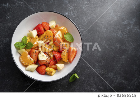 Fruit salad with fresh apple, strawberry, tangerines, pineapple and honey. Copy space. 82686518
