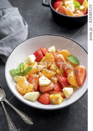 Fruit salad for breakfast, mix of with fresh apple, strawberry, tangerines, pineapple and honey. Black background Fruit salad for breakfast, mix of with fresh apple, strawberry, tangerines, pineapple and honey. Black background 82686520