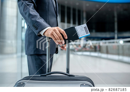 Mans hand with ticket touching handle of suitcase Mans hand with ticket touching handle of suitcase 82687185