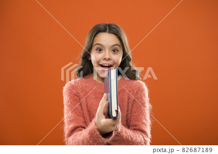 Childrens literature. Girl hold book read story over orange background. Childrens literature. Girl hold book read story over orange background. 82687189