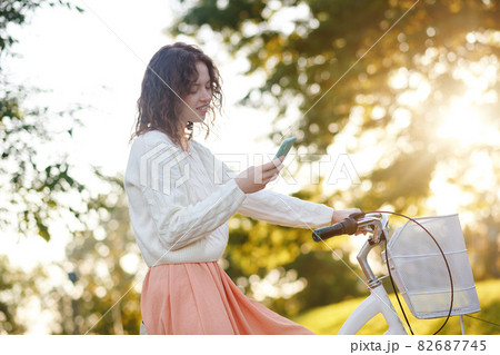 A young girl in a park with a smartphone in hands 82687745