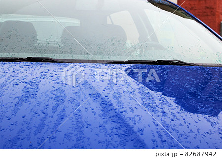Blue car hood with raindrops close up 82687942