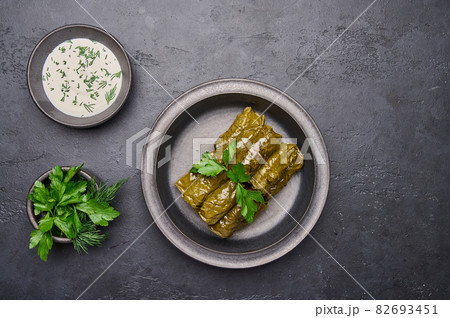 Top view dolma, parsley, saucepan with sour cream on ceramic color graphite plate Top view dolma, parsley, saucepan with sour cream on ceramic color graphite plate 82693451