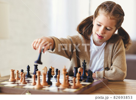 Cute little girl playing chess while spending leisure time at home during during day time Cute little girl playing chess while spending leisure time at home during during day time 82693853