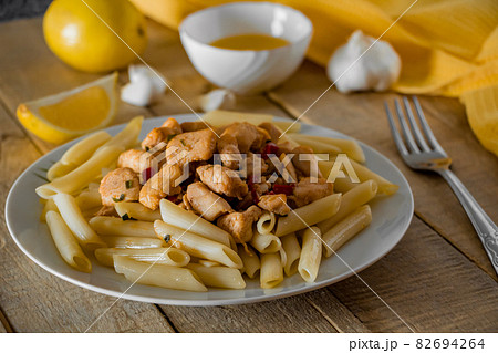 Penne pasta with appetizing chicken in a creamy sauce on a light wooden background. 82694264