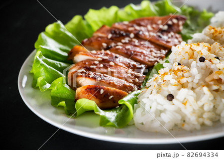 Homemade food - teriyaki chicken with white rice and pepper on a black background. Homemade food - teriyaki chicken with white rice and pepper on a black background. 82694334