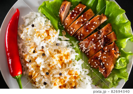 Homemade food - teriyaki chicken with white rice and pepper on a black background. Homemade food - teriyaki chicken with white rice and pepper on a black background. 82694340