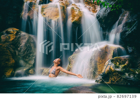 Wellness spa waterfall woman with open arms in freedom relaxing in nature waterfall. Relaxation in paradise tropical vacation. Hawaii holiday destination Wellness spa waterfall woman with open arms in freedom relaxing in nature waterfall. Relaxation in paradise tropical vacation. Hawaii holiday destination 82697139