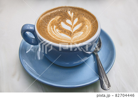 Chai Latte art in cappuccino coffee cup at cafe table. Closeup of rosetta flower drawing in foam 82704446