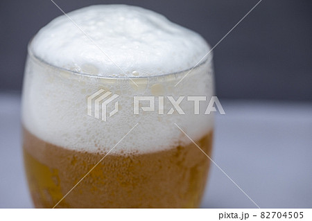 グレーの背景に映えるビール グラスに注がれるビール グレーの背景に映えるビール グラスに注がれるビール 82704505