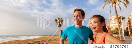 Healthy happy active lifestyle friends or couple smiling looking away on beach banner background. runners outside on fitness jog. Multiracial group, Asian woman, Caucasian man. Ethnic diversity Healthy happy active lifestyle friends or couple smiling looking away on beach banner background. runners outside on fitness jog. Multiracial group, Asian woman, Caucasian man. Ethnic diversity 82706795