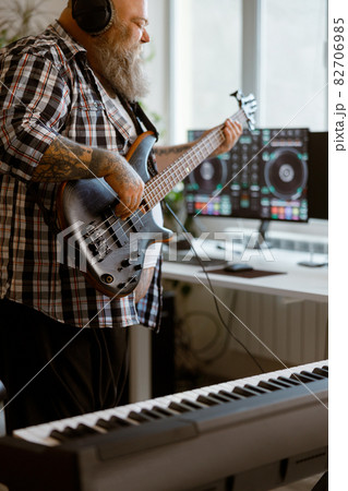 Inspired man plays electric guitar recording music with modern equipment at home 82706985