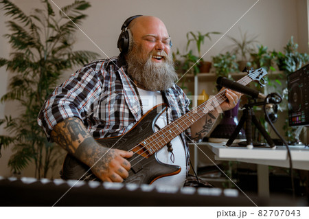 Joyful guitarist with overweight plays music recording new song in home studio 82707043