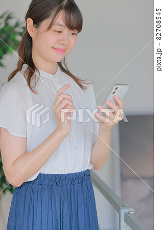 スマホを見て微笑む女性 82708545