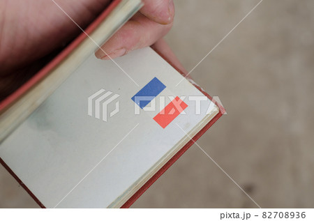 The hand holds an open pocket guide with the flag of France. A s The hand holds an open pocket guide with the flag of France. A s 82708936