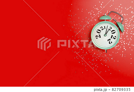 New Year 2022 banner background concept. 2021 changes to 2022 on an alarm clock on a red background with festive glitter on New Year's Eve and Christmas. 82709335