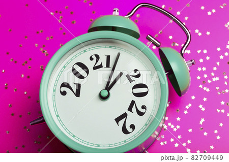 New Year 2022 background concept. 2021 changes to 2022 on an alarm clock on a pink background with festive glitter on New Year's Eve and Christmas. 82709449