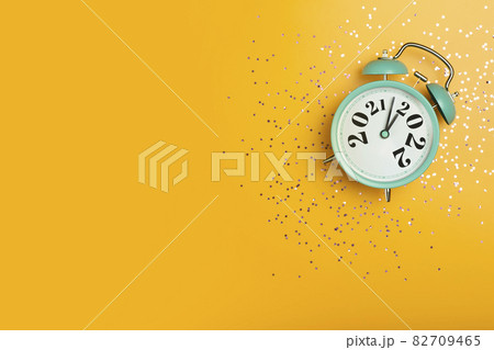 New Year 2022 banner background concept. 2021 changes to 2022 on an alarm clock on a yellow background with festive glitter on New Year's Eve and Christmas. 82709465