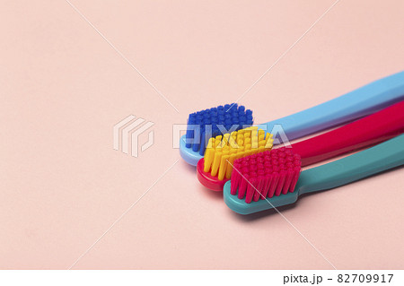 Toothbrushes of different colors on a pink background. Brushing teeth and oral hygiene. 82709917