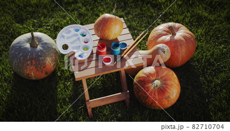 Preparing for Halloween: There is a painting set and a pumpkin on the lawn. 82710704