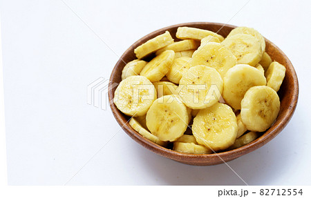 Banana slices in wooden bowl on white background. 82712554