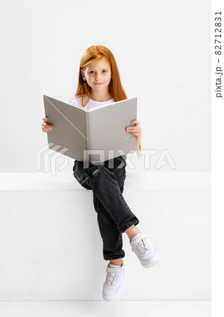 Portrait of little Caucasian preschool girl with book posing isolated over white studio background. 82712831