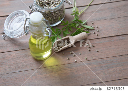 Oil from the hemp plant in a glass bottle with seeds and stems of hemp on a wooden background. The concept of an alternative vegetable oil 82713503