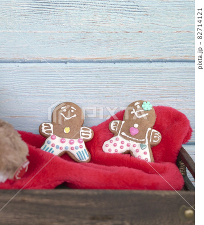 Gingerbread man cookies on top of santa red sock against wooden wall 82714121