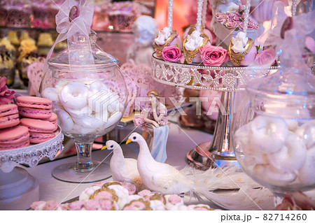 Delicious desserts at the wedding candy bar in the buffet area: statuette, figurine, cake pops, marshmallows, meringue. Delicious desserts at the wedding candy bar in the buffet area: statuette, figurine, cake pops, marshmallows, meringue. 82714260