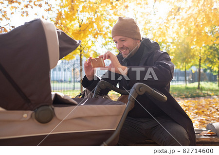 Father with baby In Park taking a photo by mobile phone Father with baby In Park taking a photo by mobile phone 82714600