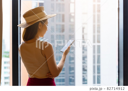 Portrait rear view of woman standing close to the window in hotel room after check-in 82714912