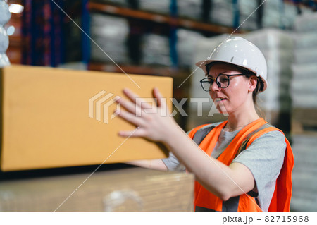 A Caucasian warehouse worker stacking the box on the pallet working in a large distribution center. 82715968