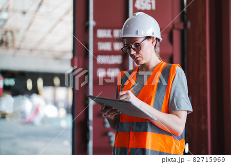 Warehouse worker working process checking the package using a tablet in a large warehouse distribution center. Caucasian female inspects cargo inventory. 82715969