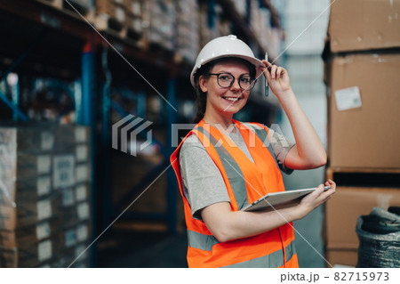 Portrait of a warehouse worker standing in a distribution center. Caucasian female looking at camera. concept of occupation and career. Portrait of a warehouse worker standing in a distribution center. Caucasian female looking at camera. concept of occupation and career. 82715973